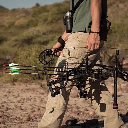 Bow hunter carrying a compound bow with arrows in the bushveld
