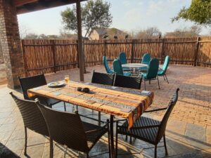 Paved outdoor dining area inside a wooden boma fence