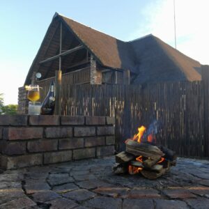 Fire burning in the boma at dusk beside a thatched chalet