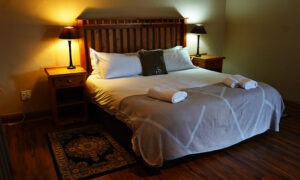 Double bed with a carved wooden headboard at the lodge