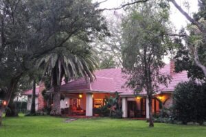 Lodge building with a red roof across a lawn at dusk
